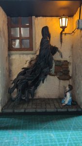 Diorama artesanal de "La Aparición de Saucedilla": escena de misterio y terror rural en miniatura con figuras detalladas, arquitectura antigua y atmósfera de leyenda