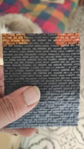 Diorama de una calle de París con fachadas de ladrillo, iluminación LED cálida y perspectiva forzada.