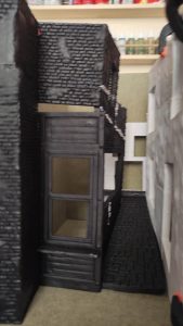 Diorama de una calle de París con fachadas de ladrillo, iluminación LED cálida y perspectiva forzada.