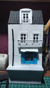 Diorama de una calle de París con fachadas de ladrillo, iluminación LED cálida y perspectiva forzada.