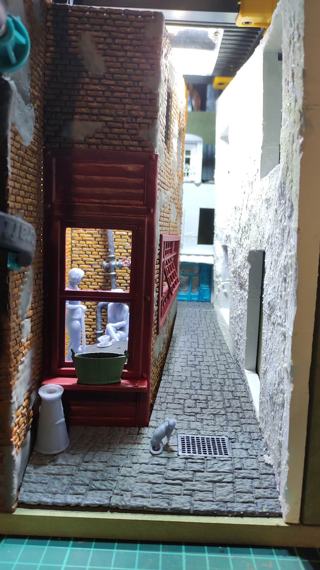 Diorama de una calle de París con fachadas de ladrillo, iluminación LED cálida y perspectiva forzada.