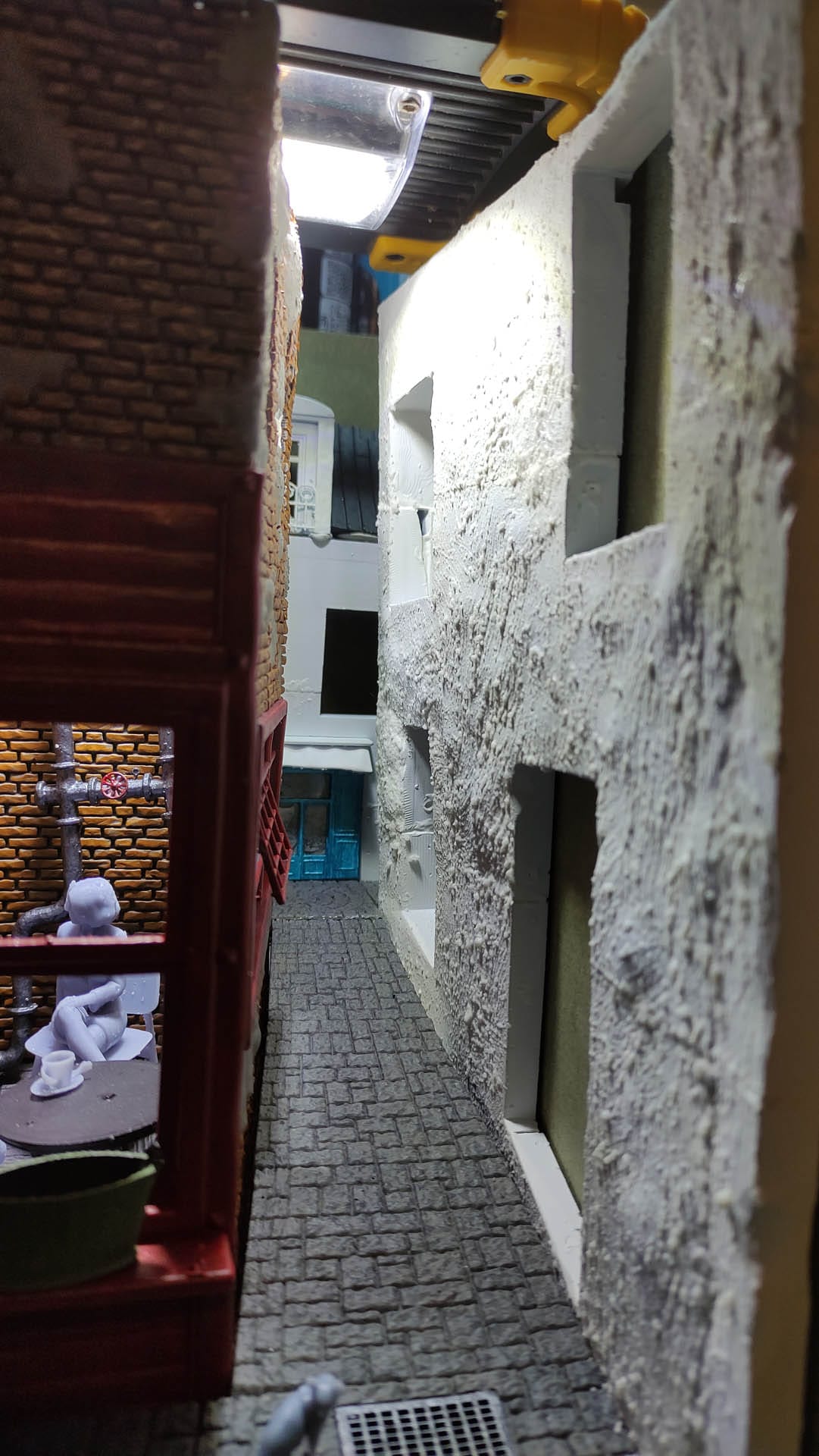 Diorama de una calle de París con fachadas de ladrillo, iluminación LED cálida y perspectiva forzada.