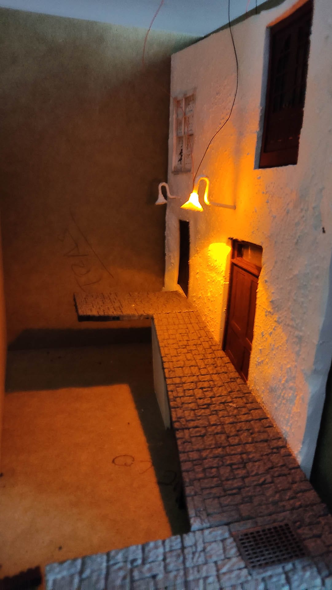 Diorama de una calle de París con fachadas de ladrillo, iluminación LED cálida y perspectiva forzada.