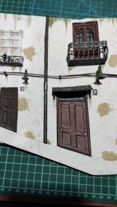 Diorama de una calle de París con fachadas de ladrillo, iluminación LED cálida y perspectiva forzada.