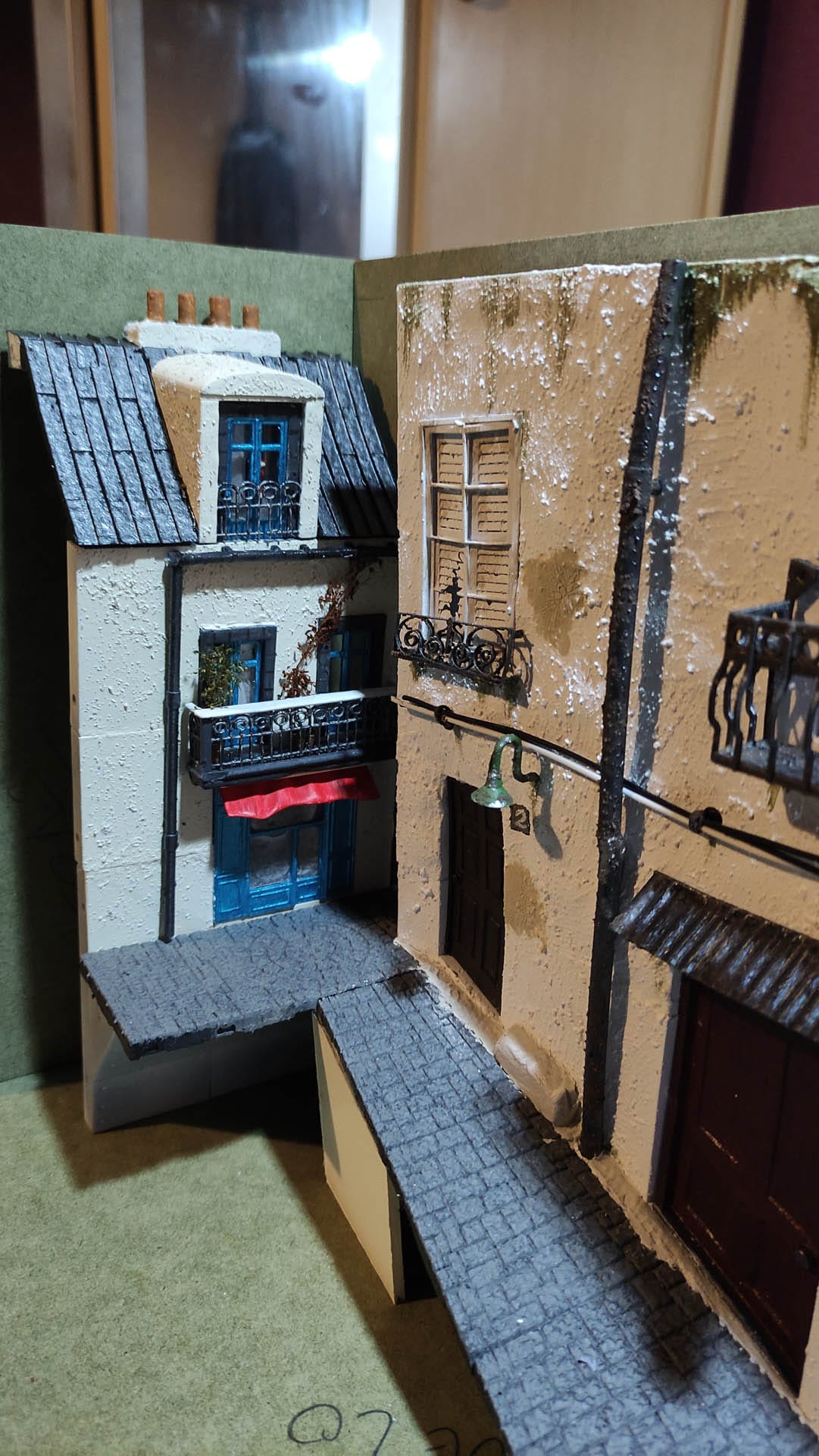 Diorama de una calle de París con fachadas de ladrillo, iluminación LED cálida y perspectiva forzada.