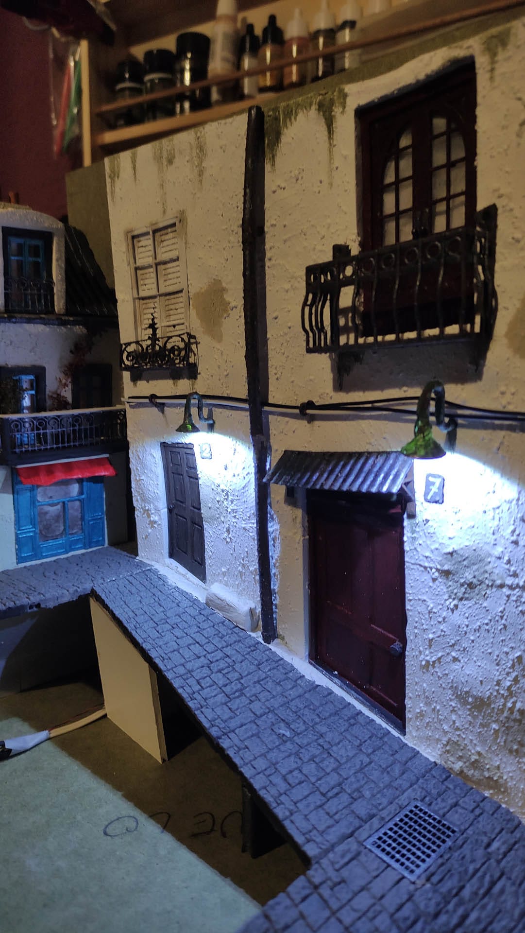 Diorama de una calle de París con fachadas de ladrillo, iluminación LED cálida y perspectiva forzada.