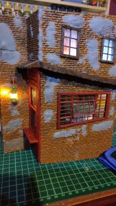 Diorama de una calle de París con fachadas de ladrillo, iluminación LED cálida y perspectiva forzada.