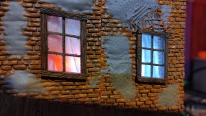 Diorama de una calle de París con fachadas de ladrillo, iluminación LED cálida y perspectiva forzada.