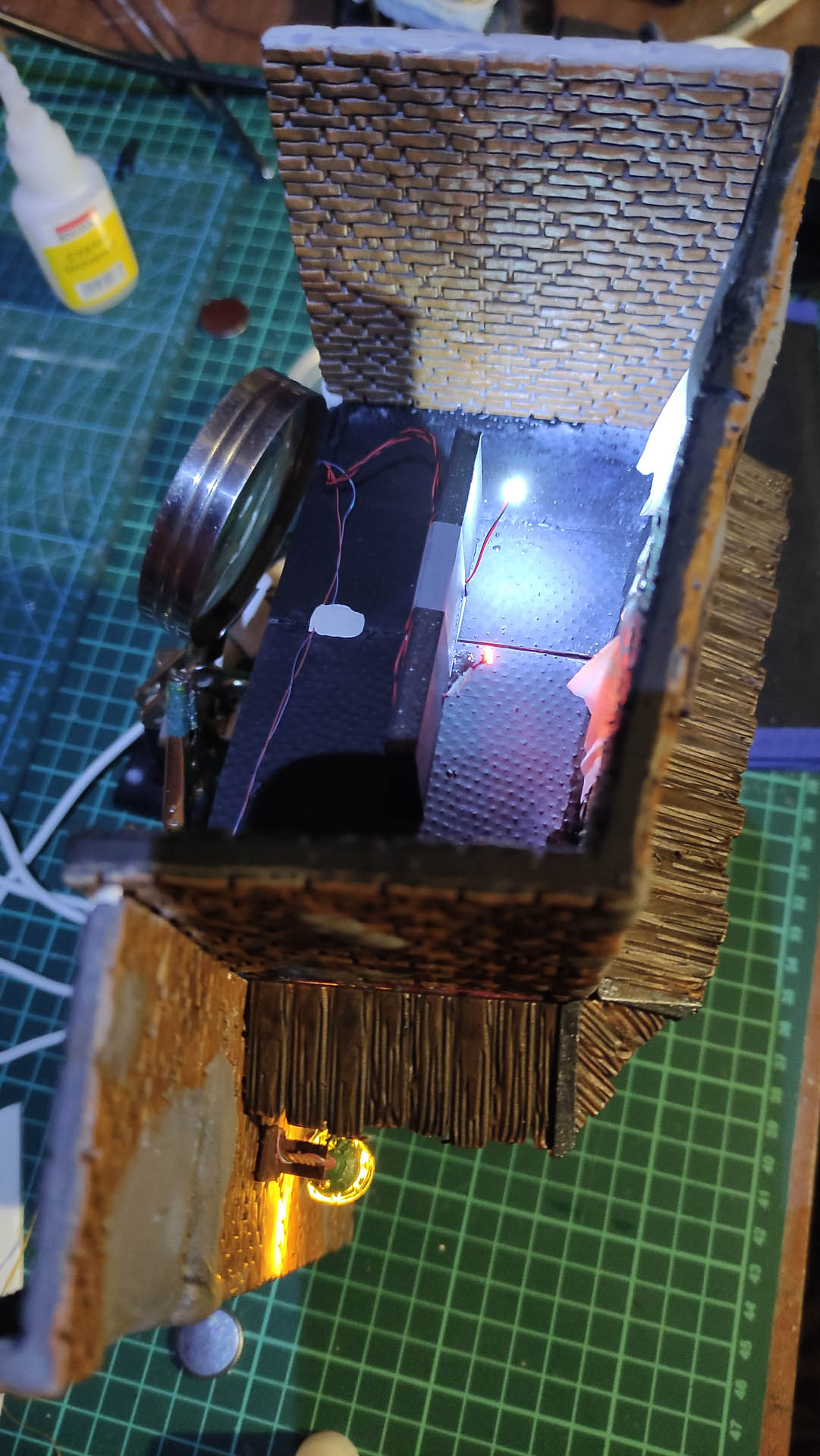 Diorama de una calle de París con fachadas de ladrillo, iluminación LED cálida y perspectiva forzada.