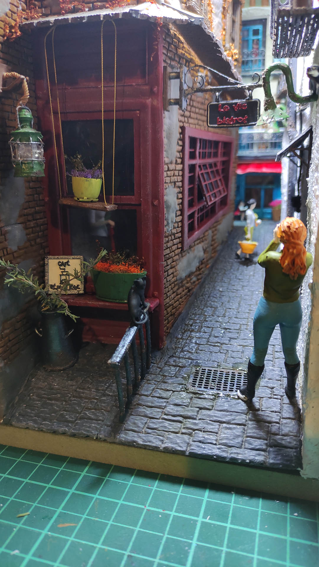 Diorama de una calle de París con fachadas de ladrillo, iluminación LED cálida y perspectiva forzada.