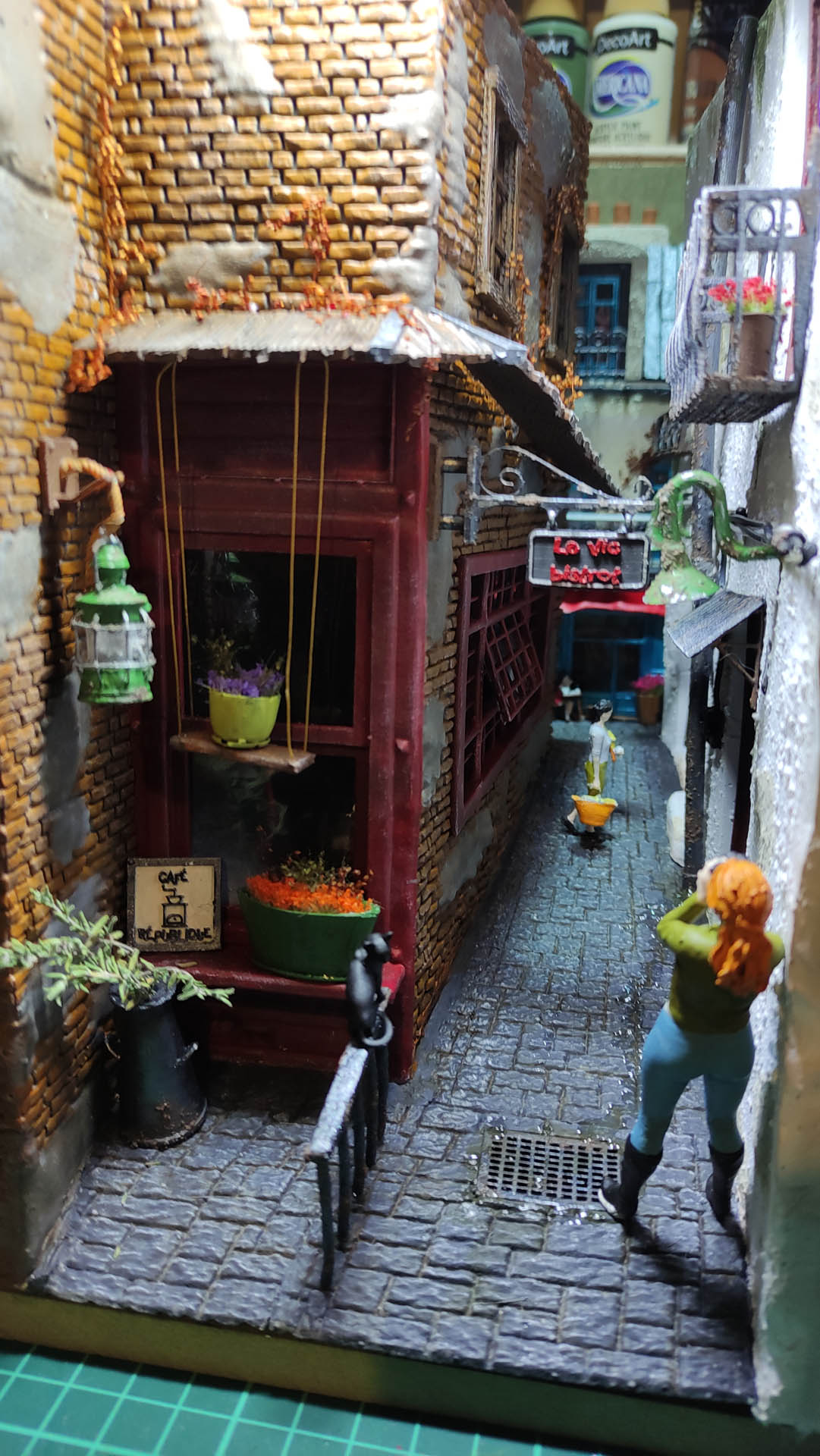 Diorama de una calle de París con fachadas de ladrillo, iluminación LED cálida y perspectiva forzada.