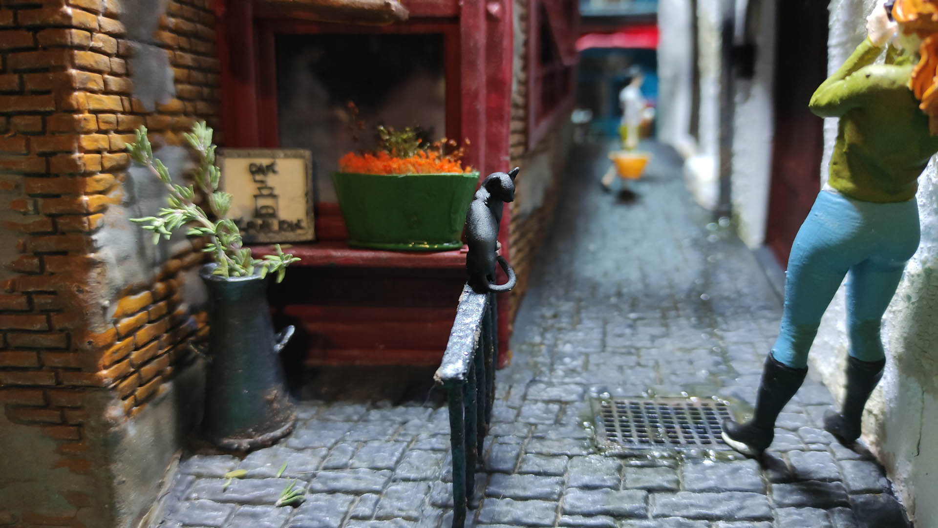 Diorama de una calle de París con fachadas de ladrillo, iluminación LED cálida y perspectiva forzada.