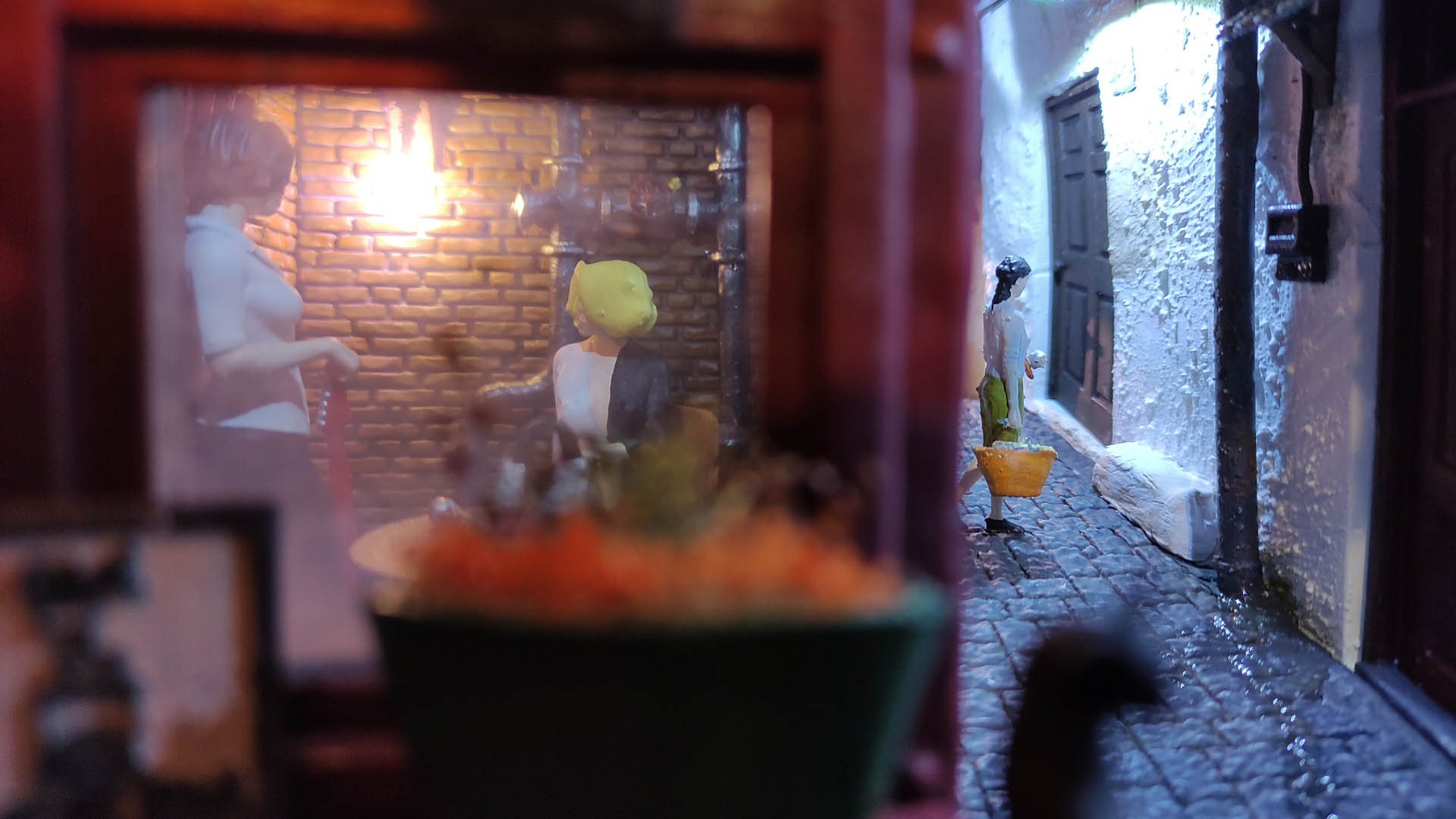 Diorama de una calle de París con fachadas de ladrillo, iluminación LED cálida y perspectiva forzada.