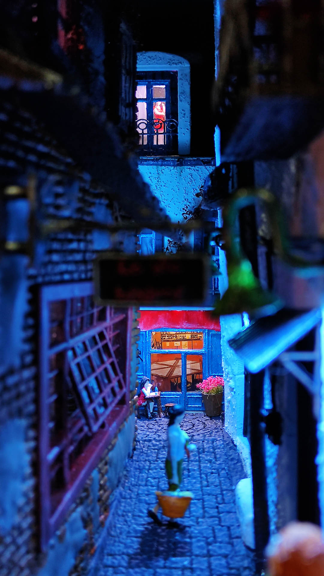 Diorama de una calle de París con fachadas de ladrillo, iluminación LED cálida y perspectiva forzada.