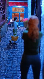 Diorama de una calle de París con fachadas de ladrillo, iluminación LED cálida y perspectiva forzada.