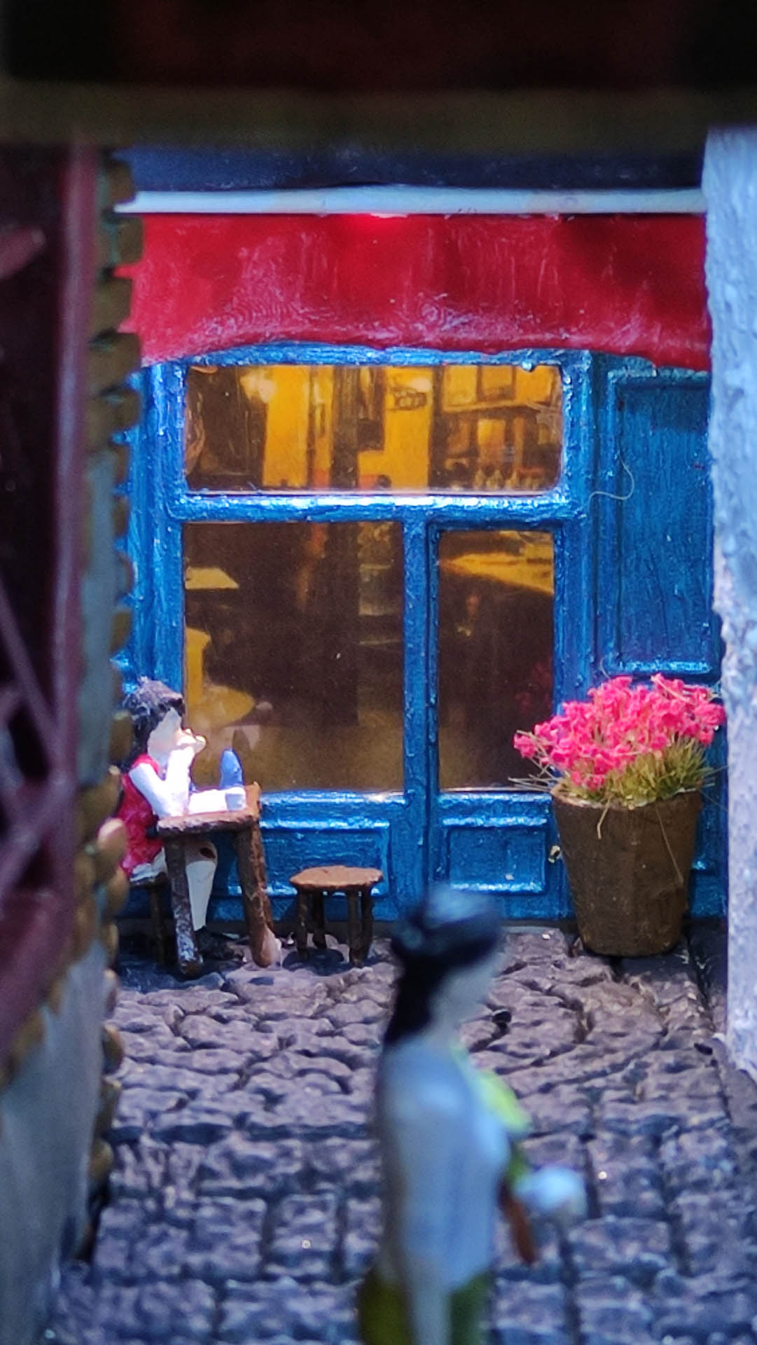 Diorama de una calle de París con fachadas de ladrillo, iluminación LED cálida y perspectiva forzada.