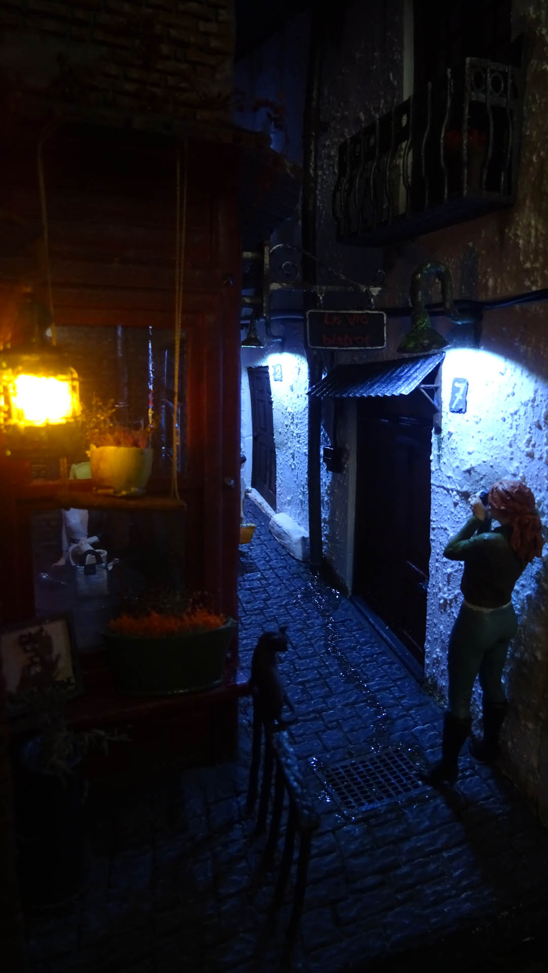 Diorama de una calle de París con fachadas de ladrillo, iluminación LED cálida y perspectiva forzada.