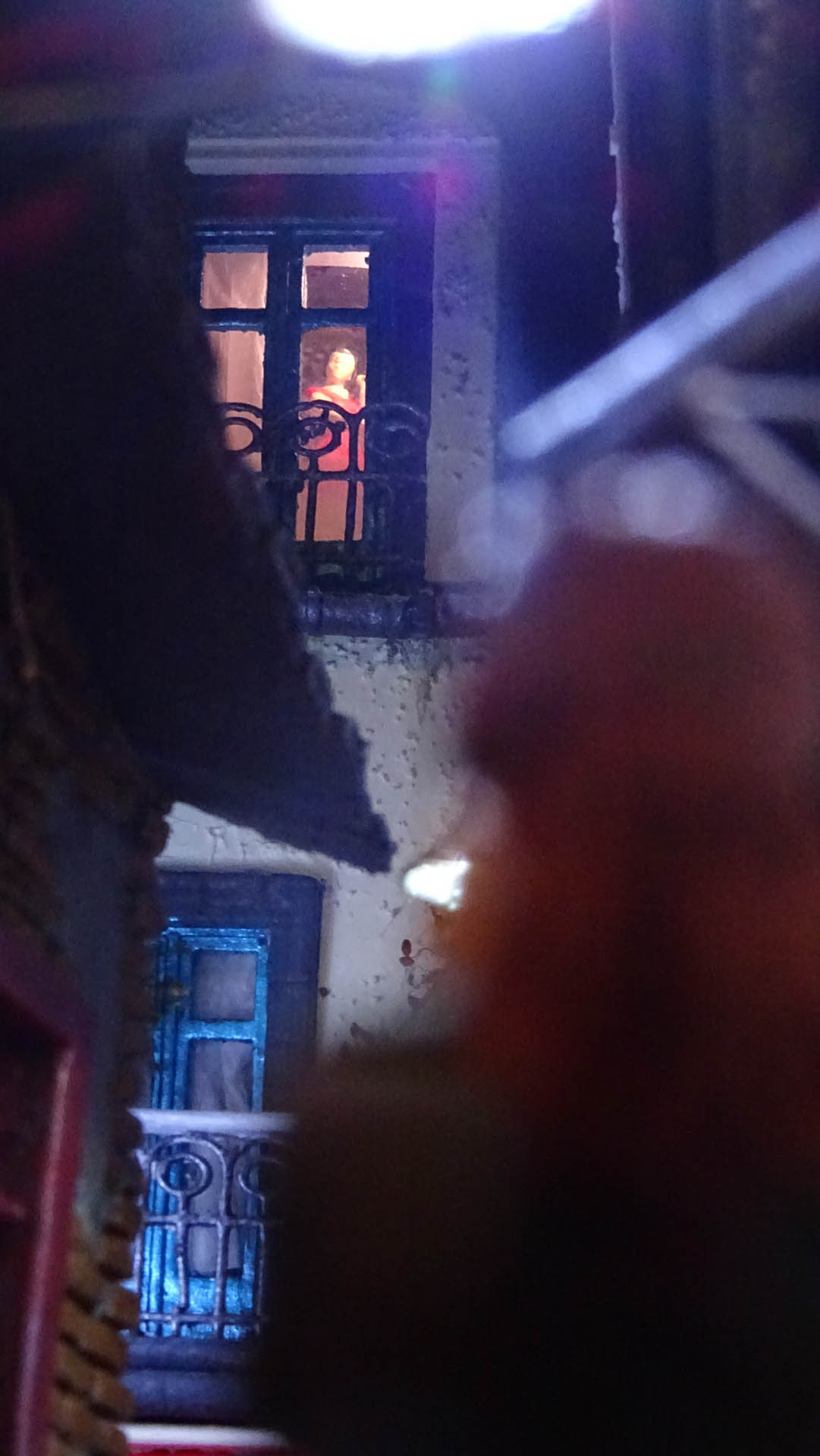 Diorama de una calle de París con fachadas de ladrillo, iluminación LED cálida y perspectiva forzada.