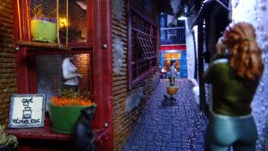 Diorama de una calle de París con fachadas de ladrillo, iluminación LED cálida y perspectiva forzada.