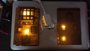 Efecto de iluminación cálida en ventanas de una fachada en miniatura para crear atmósfera de misterio