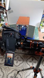 Cámara DSLR profesional capturando los detalles del diorama artesanal del hotel Overlook de El Resplandor en miniatura