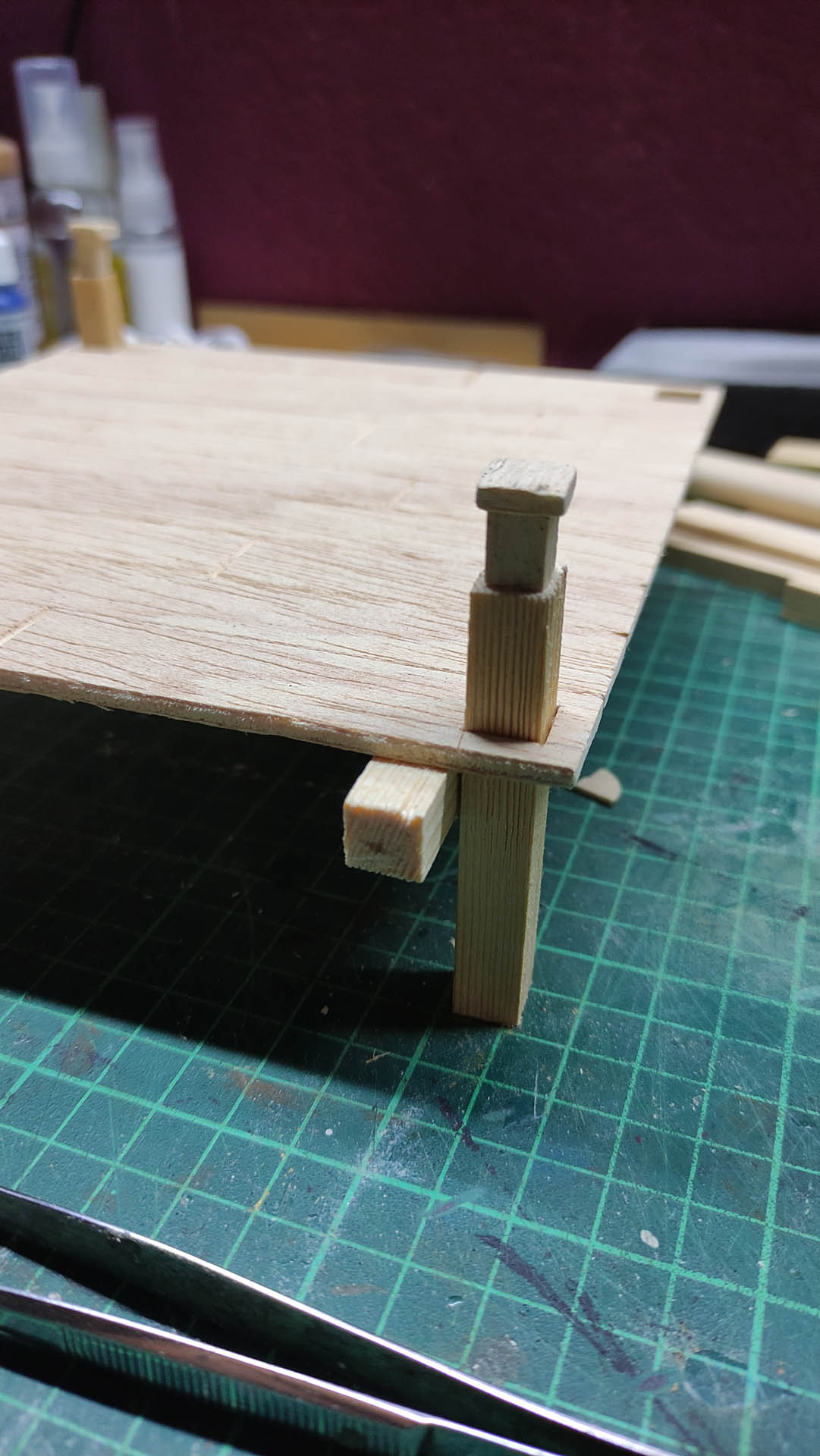 Diorama artístico de una cabaña de madera azul envejecida sobre pilotes en un pantano, con efectos de agua estancada, un bote de remos y detalles de vegetación pantanosa.