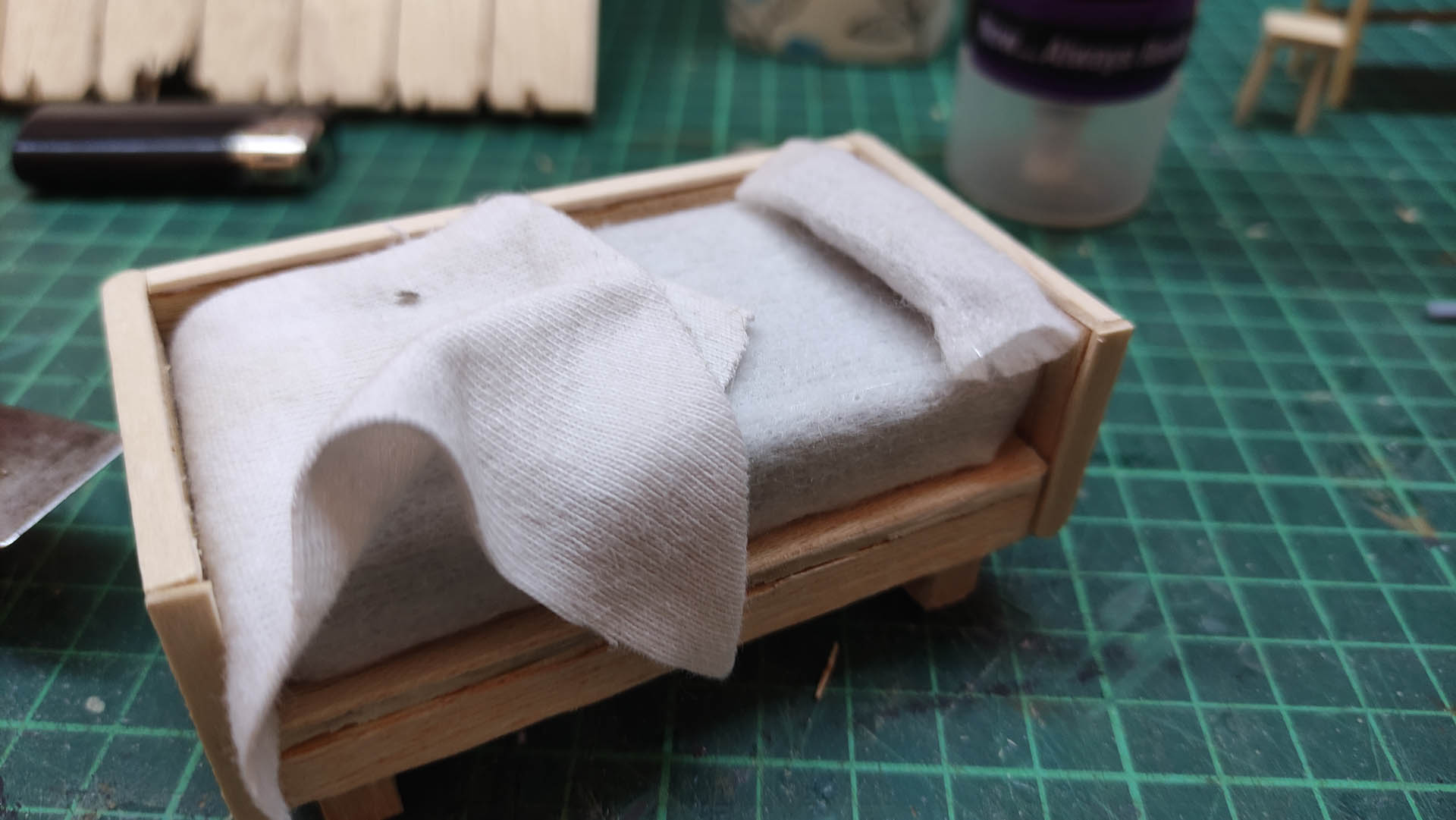 Diorama artístico de una cabaña de madera azul envejecida sobre pilotes en un pantano, con efectos de agua estancada, un bote de remos y detalles de vegetación pantanosa.