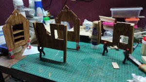 Diorama artístico de una cabaña de madera azul envejecida sobre pilotes en un pantano, con efectos de agua estancada, un bote de remos y detalles de vegetación pantanosa.