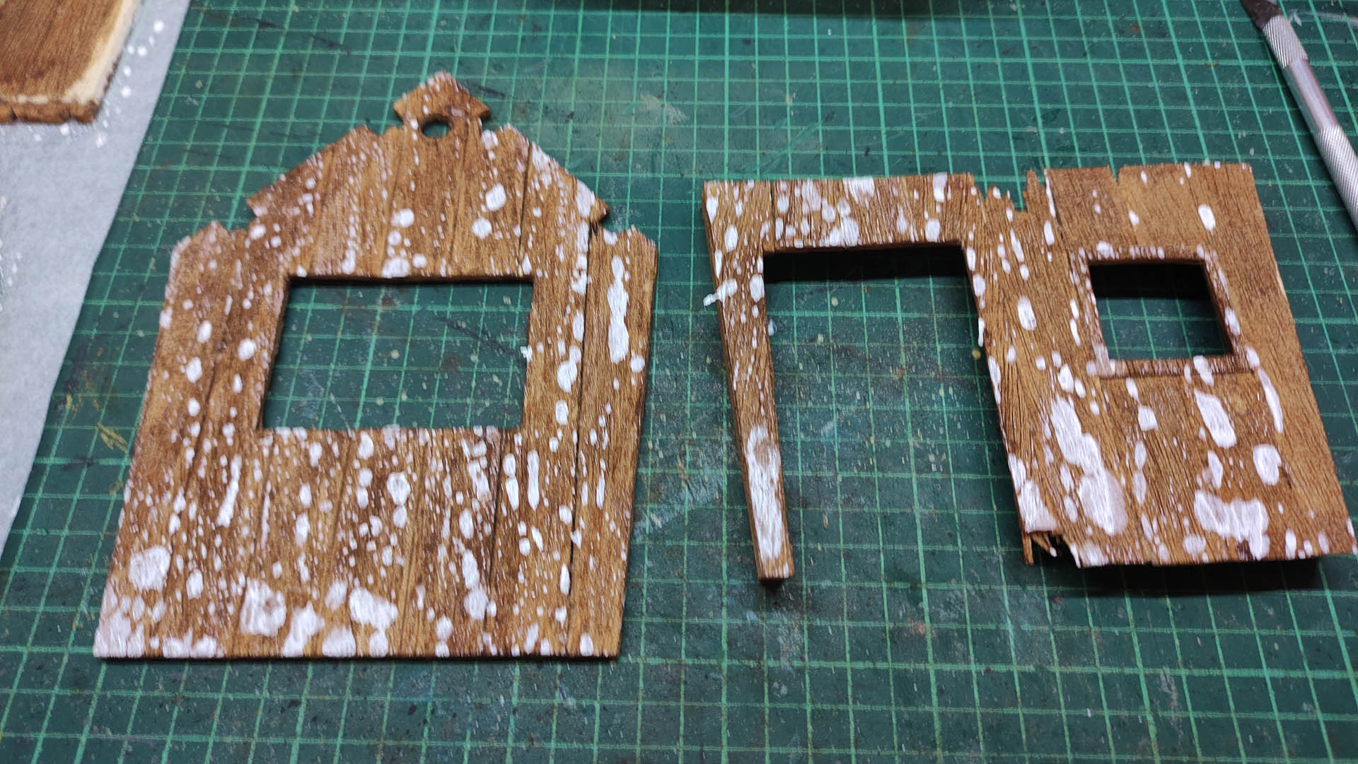 Diorama artístico de una cabaña de madera azul envejecida sobre pilotes en un pantano, con efectos de agua estancada, un bote de remos y detalles de vegetación pantanosa.