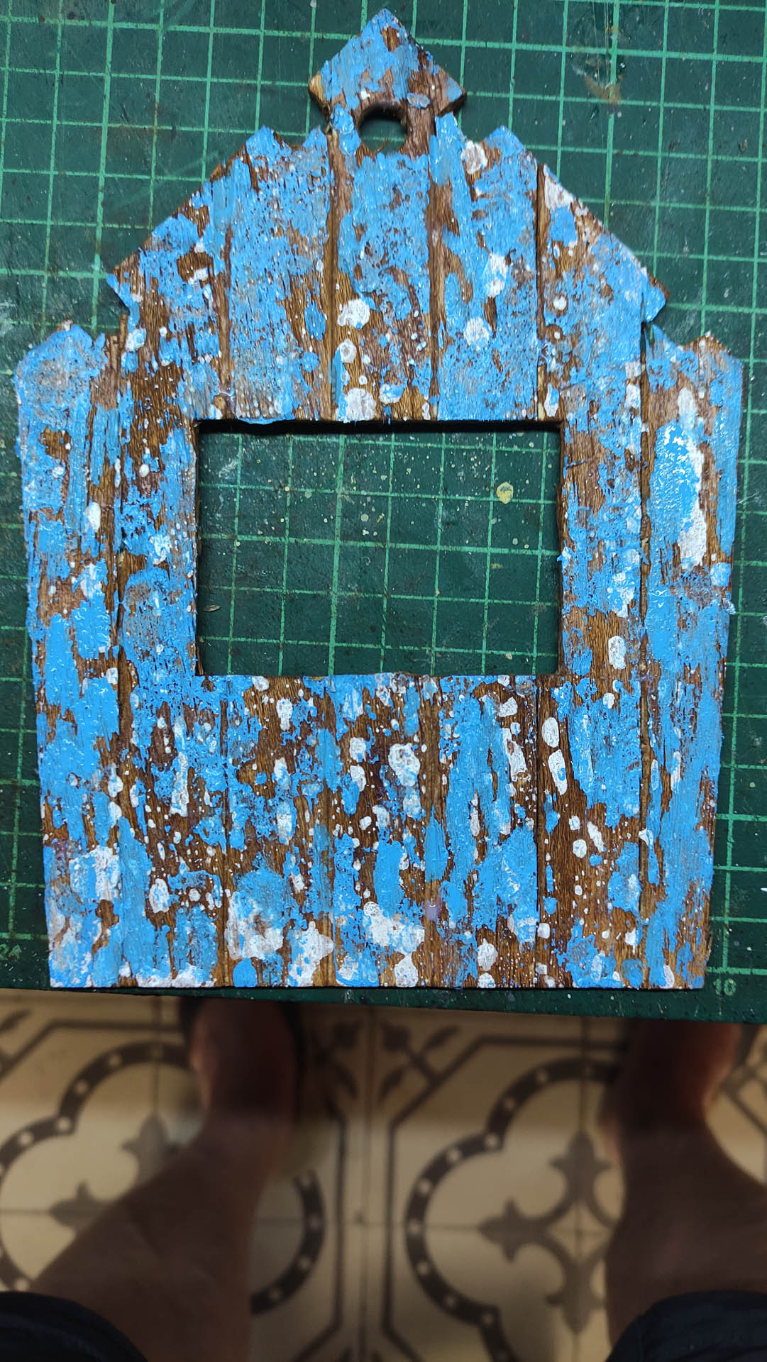 Diorama artístico de una cabaña de madera azul envejecida sobre pilotes en un pantano, con efectos de agua estancada, un bote de remos y detalles de vegetación pantanosa.