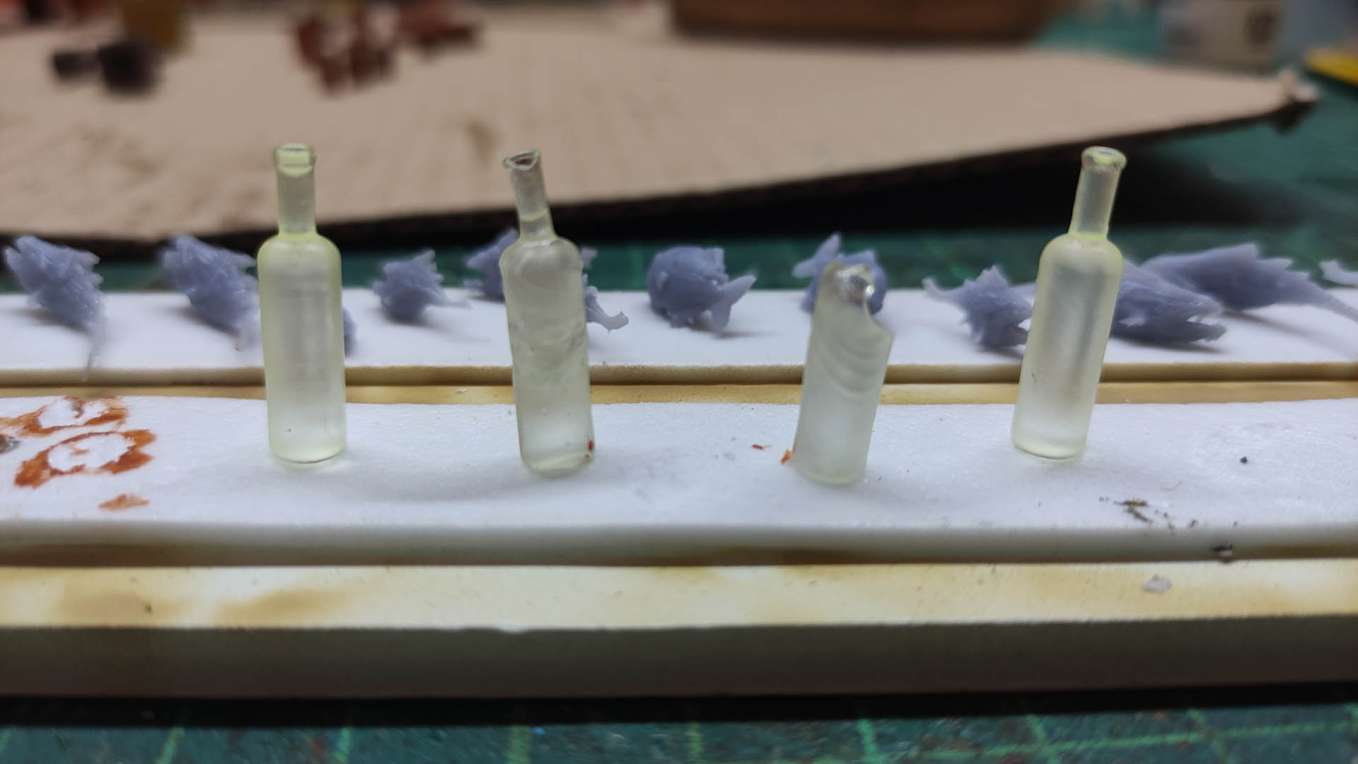 Diorama artístico de una cabaña de madera azul envejecida sobre pilotes en un pantano, con efectos de agua estancada, un bote de remos y detalles de vegetación pantanosa.