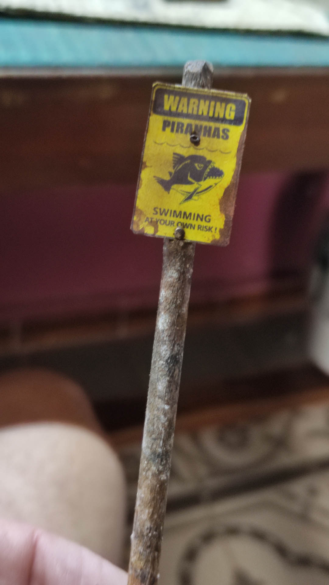 Diorama artístico de una cabaña de madera azul envejecida sobre pilotes en un pantano, con efectos de agua estancada, un bote de remos y detalles de vegetación pantanosa.