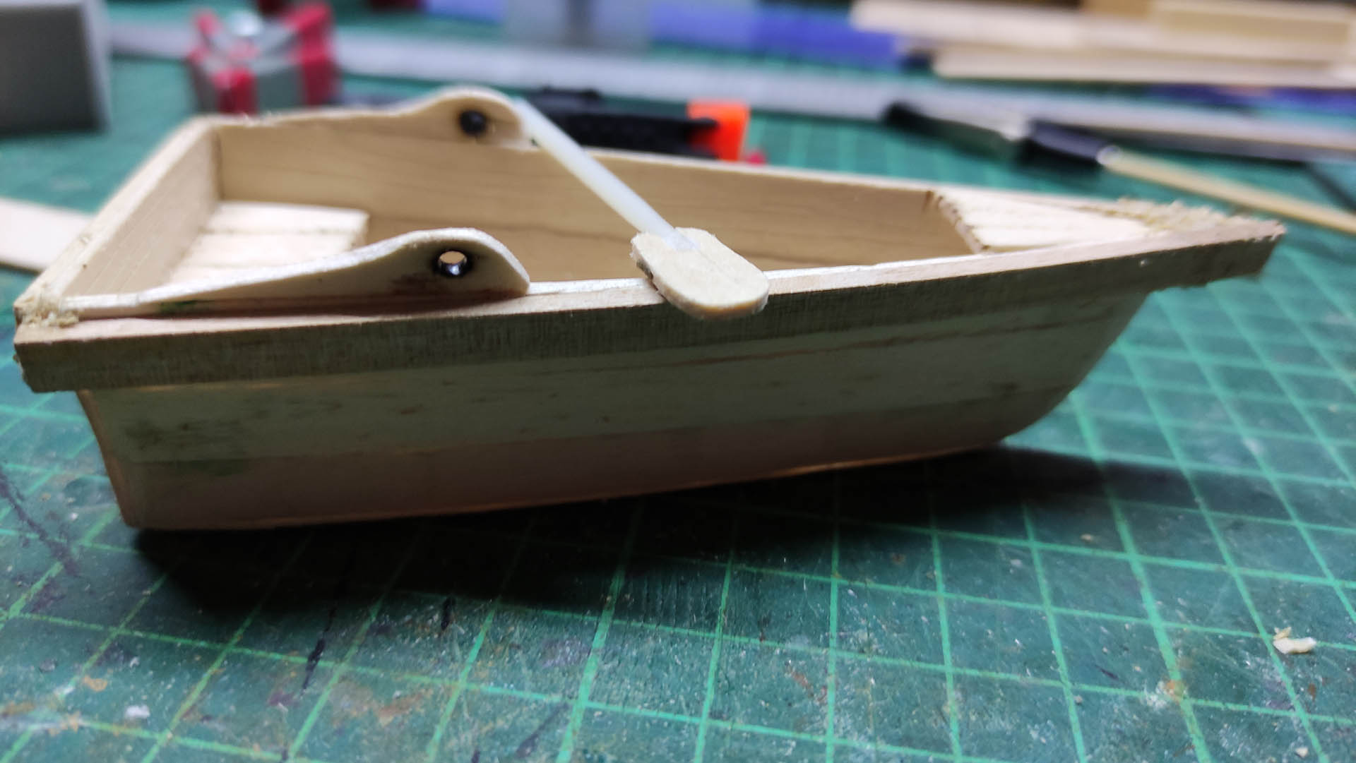 Diorama artístico de una cabaña de madera azul envejecida sobre pilotes en un pantano, con efectos de agua estancada, un bote de remos y detalles de vegetación pantanosa.