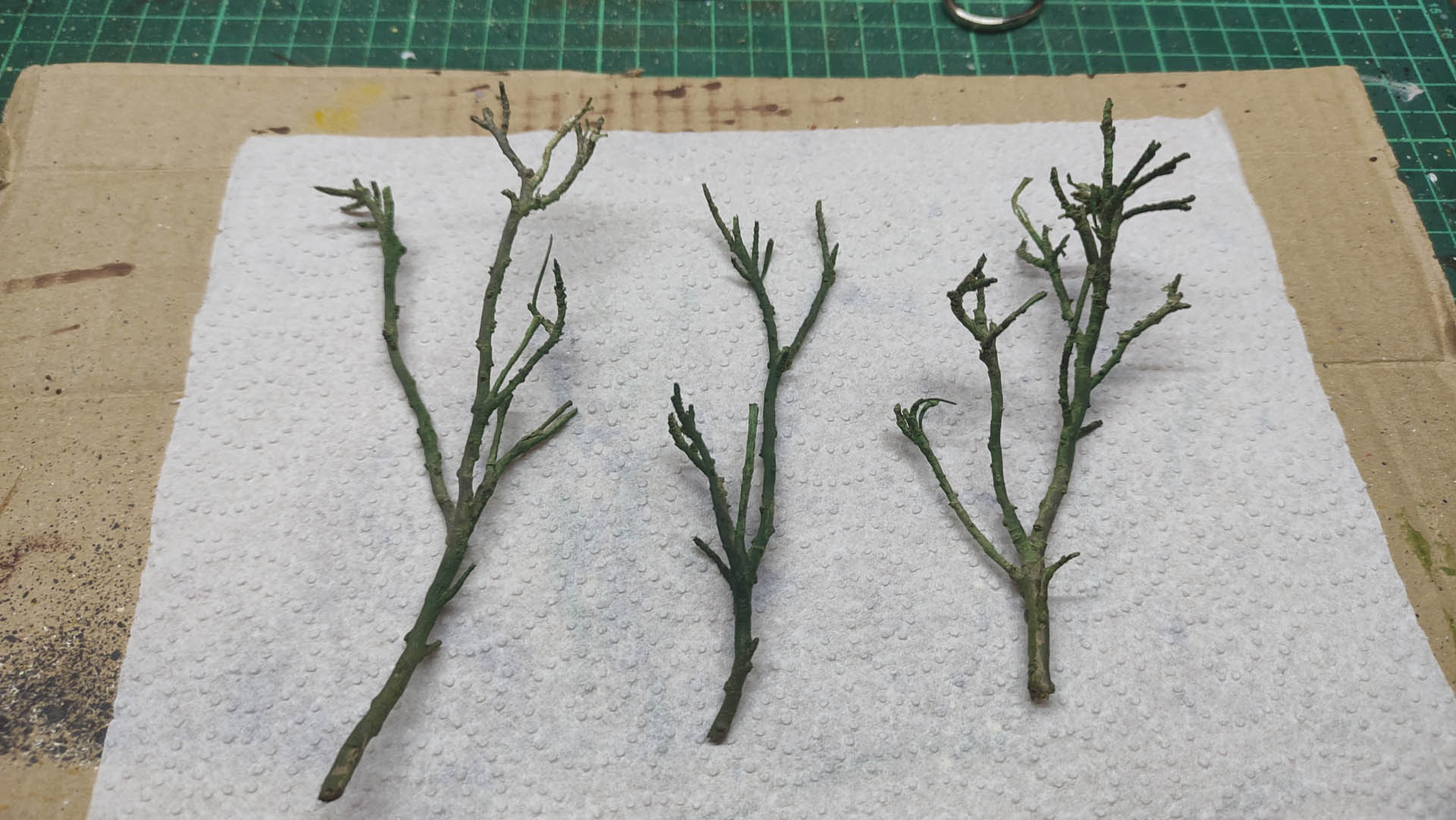 Diorama artístico de una cabaña de madera azul envejecida sobre pilotes en un pantano, con efectos de agua estancada, un bote de remos y detalles de vegetación pantanosa.