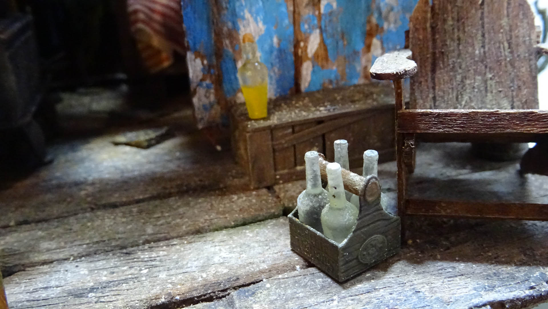 Diorama artístico de una cabaña de madera azul envejecida sobre pilotes en un pantano, con efectos de agua estancada, un bote de remos y detalles de vegetación pantanosa.