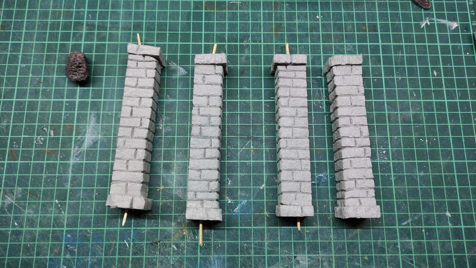 Diorama artesanal detallado de un duende y un pozo estructurado en tres niveles. El nivel superior recrea un jardín exterior exuberante utilizando vegetación natural y preservada (musgos y enredaderas), sobre estancias subterráneas de piedra y madera