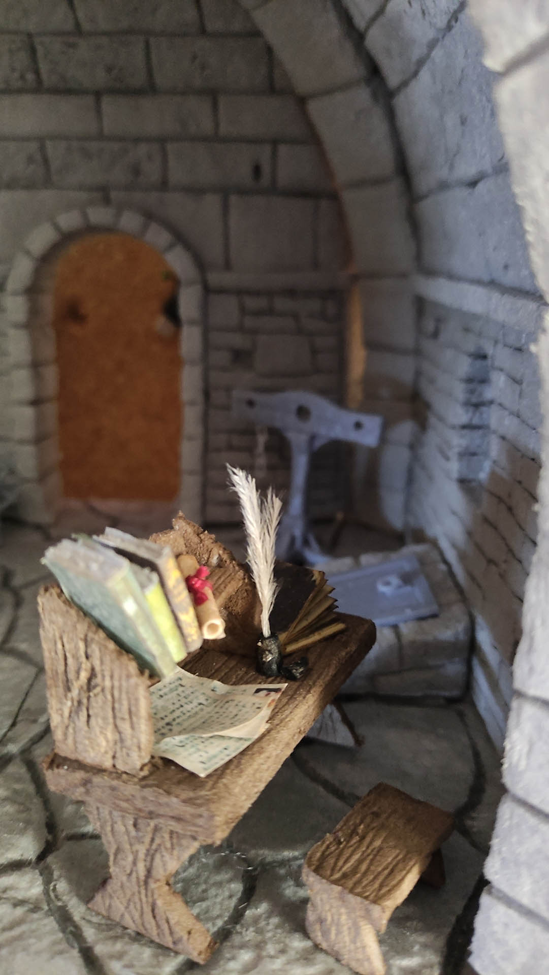 Diorama artesanal detallado de un duende y un pozo estructurado en tres niveles. El nivel superior recrea un jardín exterior exuberante utilizando vegetación natural y preservada (musgos y enredaderas), sobre estancias subterráneas de piedra y madera