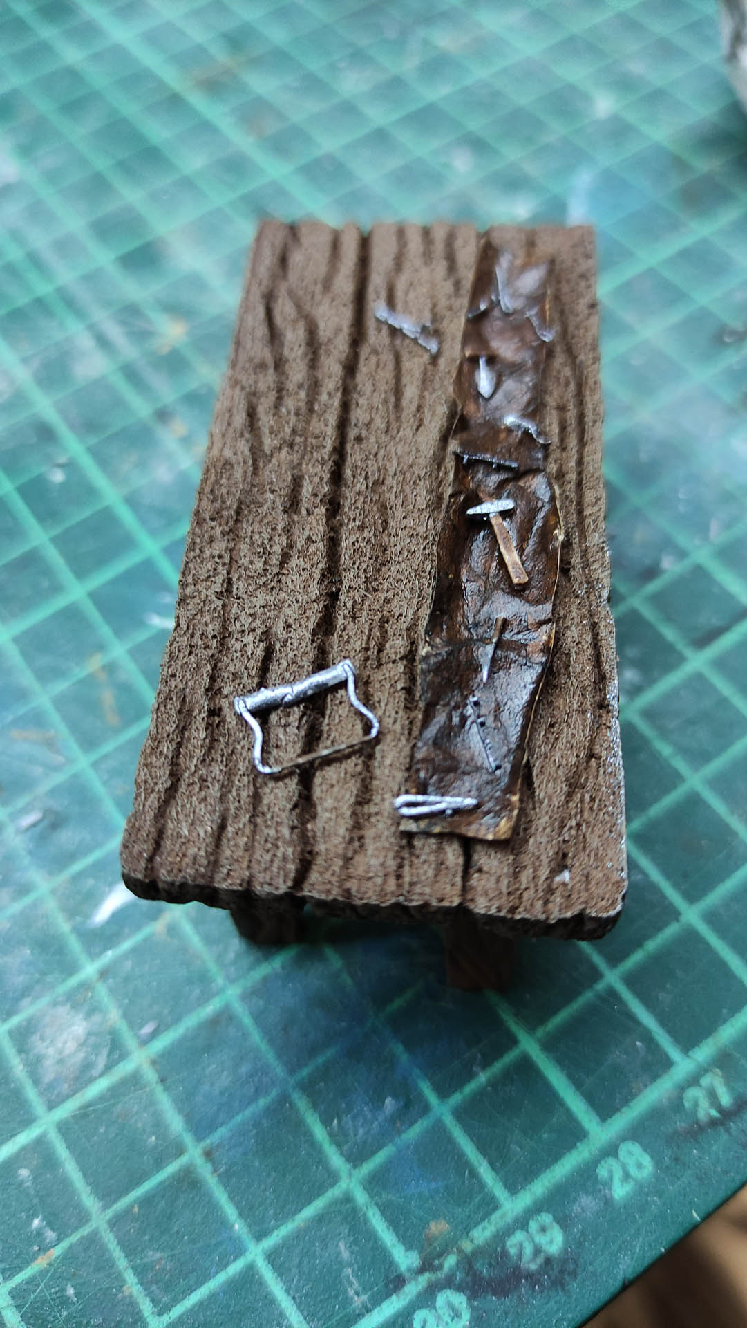 Diorama artesanal detallado de un duende y un pozo estructurado en tres niveles. El nivel superior recrea un jardín exterior exuberante utilizando vegetación natural y preservada (musgos y enredaderas), sobre estancias subterráneas de piedra y madera