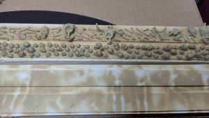 Diorama artesanal detallado de un duende y un pozo estructurado en tres niveles. El nivel superior recrea un jardín exterior exuberante utilizando vegetación natural y preservada (musgos y enredaderas), sobre estancias subterráneas de piedra y madera