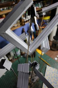 Proceso de construcción del diorama "Las Gemelas": recreación artesanal del pasillo del hotel Overlook con papel pintado geométrico en miniatura, carpintería detallada de puertas de hotel