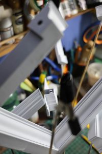 Proceso de construcción del diorama "Las Gemelas": recreación artesanal del pasillo del hotel Overlook con papel pintado geométrico en miniatura, carpintería detallada de puertas de hotel