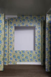 Proceso de construcción del diorama "Las Gemelas": recreación artesanal del pasillo del hotel Overlook con papel pintado geométrico en miniatura, carpintería detallada de puertas de hotel