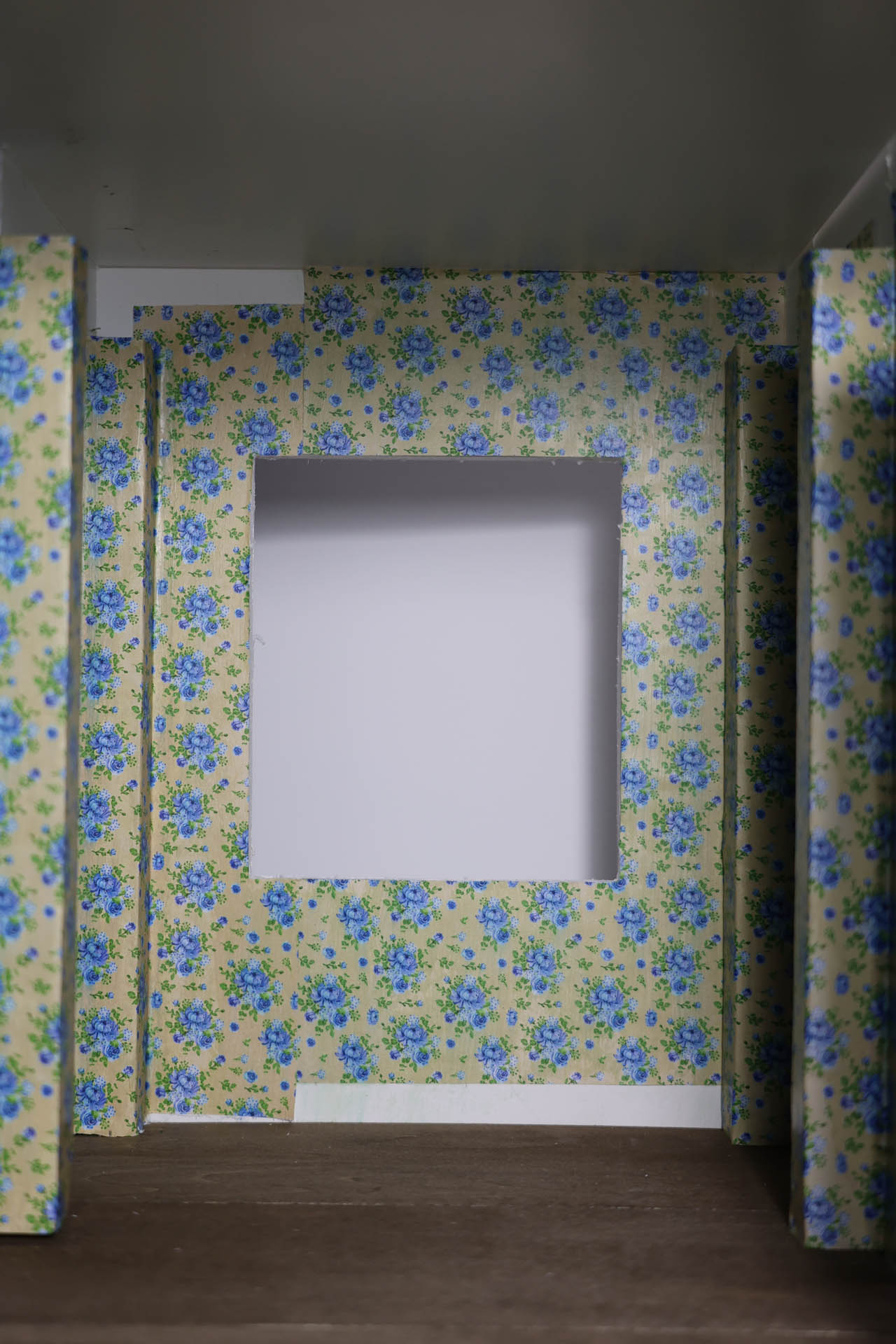 Proceso de construcción del diorama "Las Gemelas": recreación artesanal del pasillo del hotel Overlook con papel pintado geométrico en miniatura, carpintería detallada de puertas de hotel