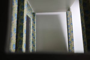 Proceso de construcción del diorama "Las Gemelas": recreación artesanal del pasillo del hotel Overlook con papel pintado geométrico en miniatura, carpintería detallada de puertas de hotel