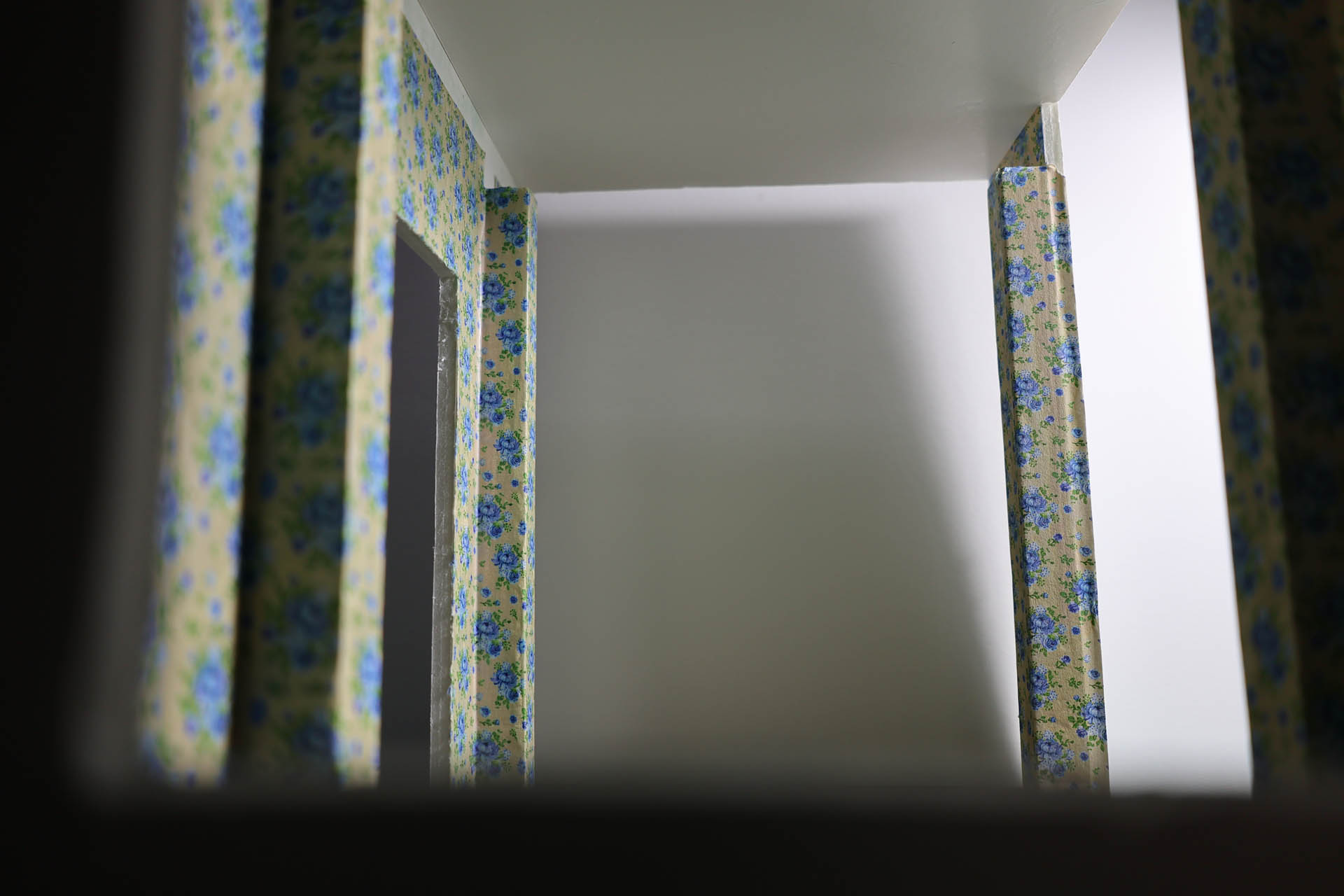 Proceso de construcción del diorama "Las Gemelas": recreación artesanal del pasillo del hotel Overlook con papel pintado geométrico en miniatura, carpintería detallada de puertas de hotel