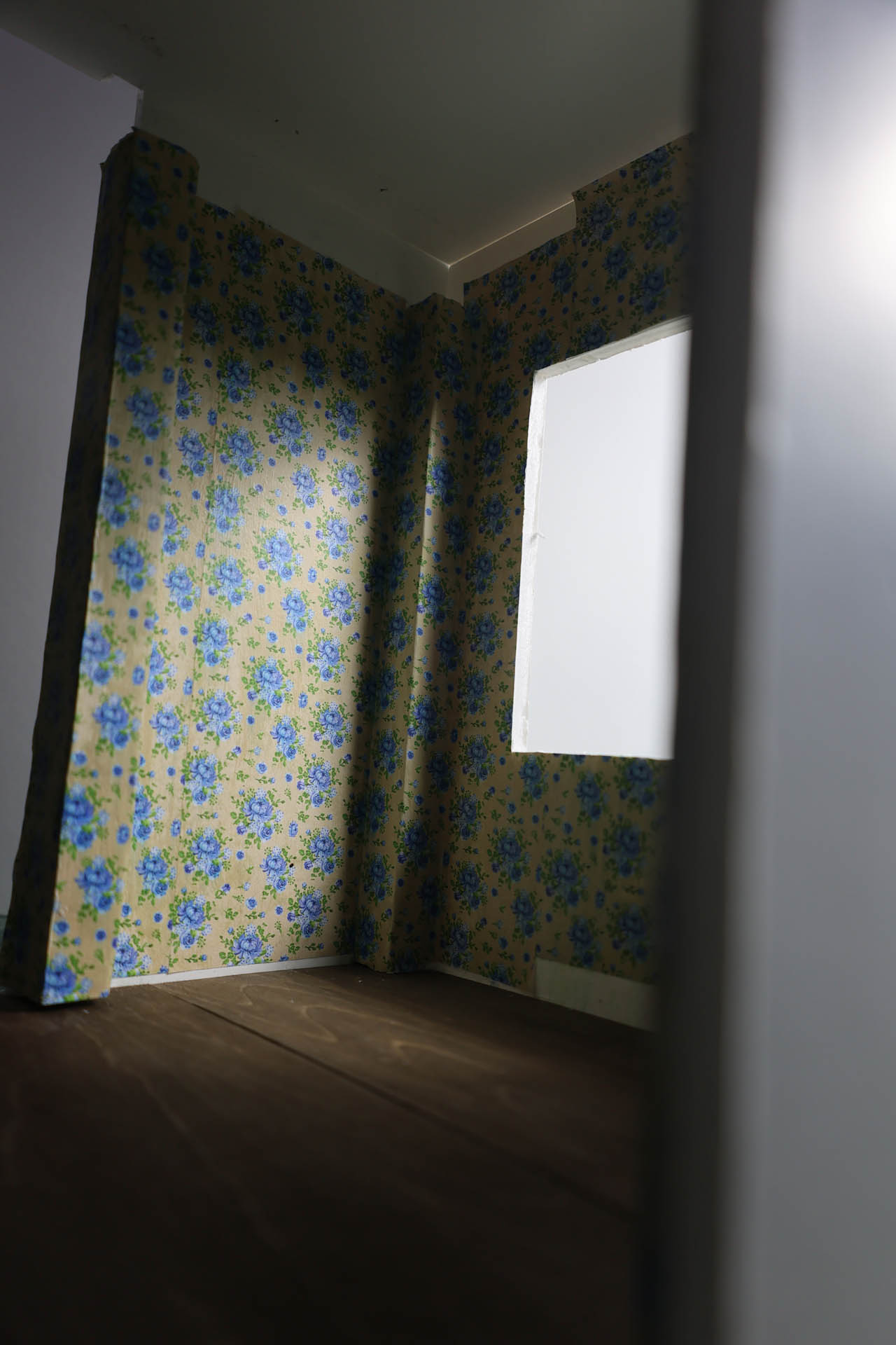 Proceso de construcción del diorama "Las Gemelas": recreación artesanal del pasillo del hotel Overlook con papel pintado geométrico en miniatura, carpintería detallada de puertas de hotel