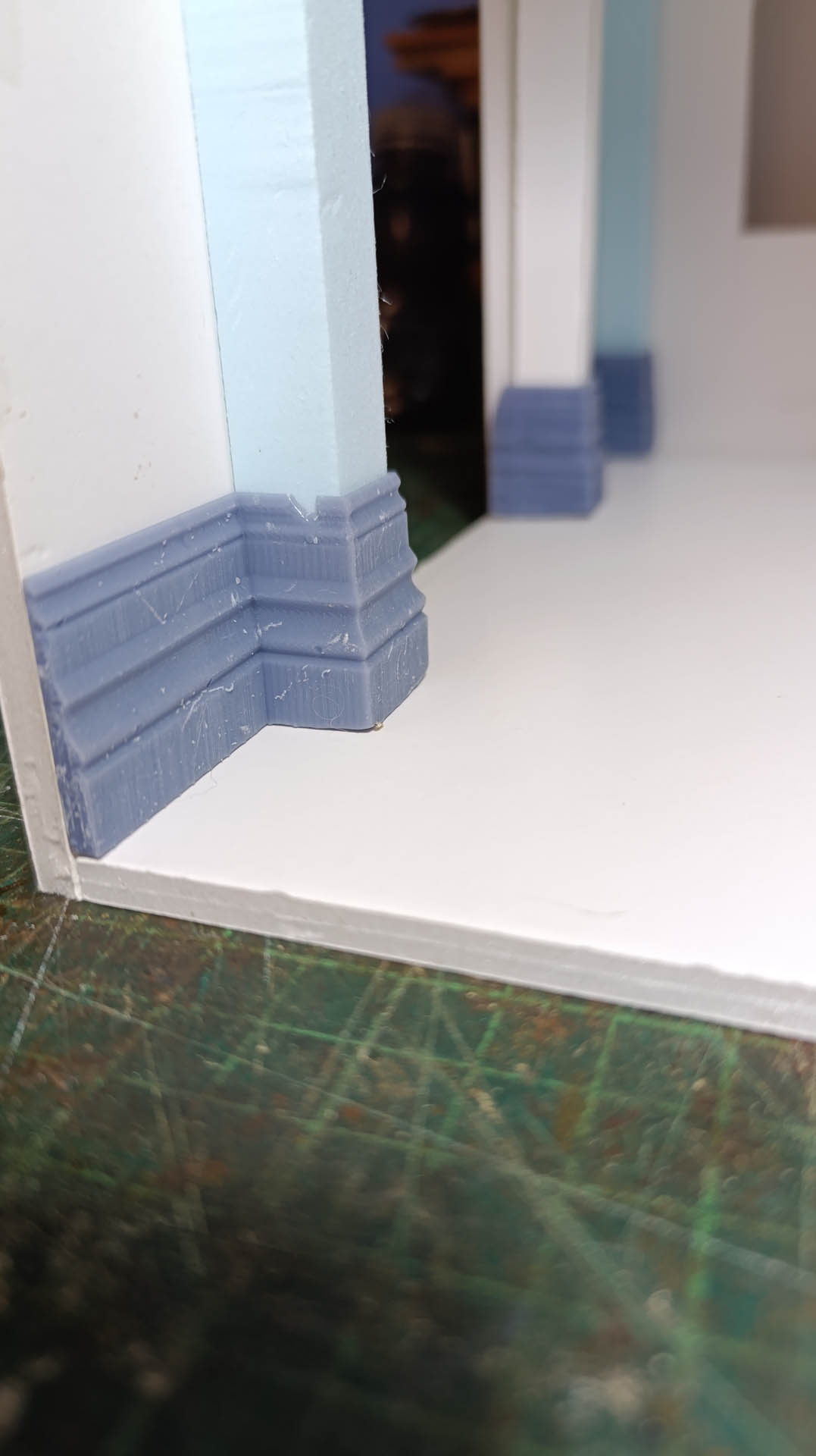 Proceso de construcción del diorama "Las Gemelas": recreación artesanal del pasillo del hotel Overlook con papel pintado geométrico en miniatura, carpintería detallada de puertas de hotel