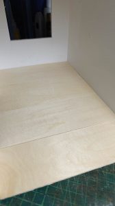 Proceso de construcción del diorama "Las Gemelas": recreación artesanal del pasillo del hotel Overlook con papel pintado geométrico en miniatura, carpintería detallada de puertas de hotel