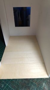 Proceso de construcción del diorama "Las Gemelas": recreación artesanal del pasillo del hotel Overlook con papel pintado geométrico en miniatura, carpintería detallada de puertas de hotel