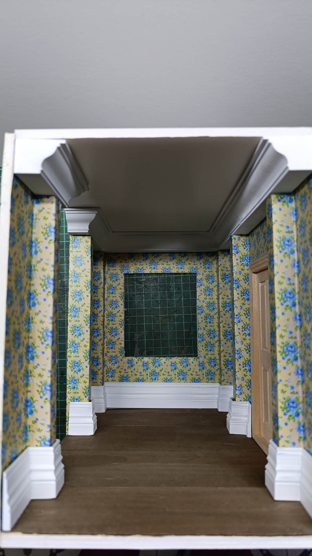 Proceso de construcción del diorama "Las Gemelas": recreación artesanal del pasillo del hotel Overlook con papel pintado geométrico en miniatura, carpintería detallada de puertas de hotel